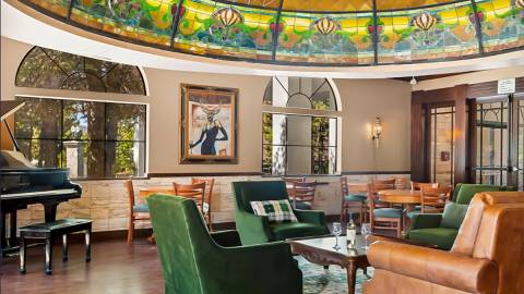 Una foto del interior del Tiffany's Bistro en el Chateau Big Bear: se ven sillas de tela y de cuero bajo su cúpula Tiffany.
