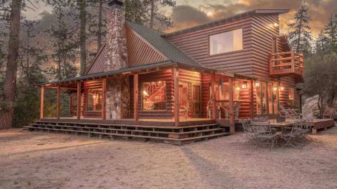 Una cabaña Maltby en el bosque, con un exterior de rica madera, chimenea de piedra y cristales transparentes.